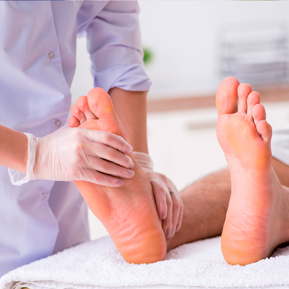 A podiatrist wearing gloves examines and applies pressure to a patient's feet during a check-up - Podiatrist Visalia